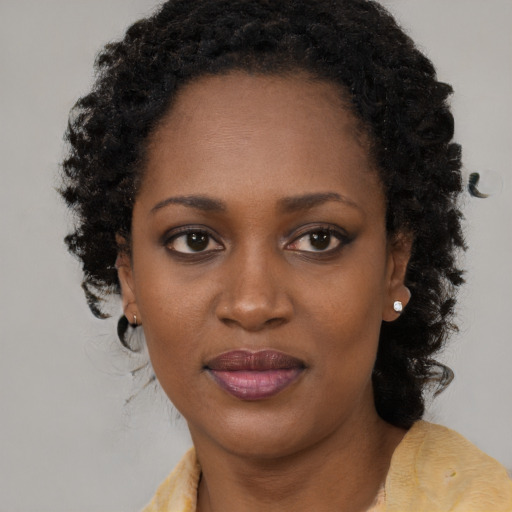 Joyful black young-adult female with long  brown hair and brown eyes