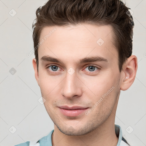 Joyful white young-adult male with short  brown hair and grey eyes