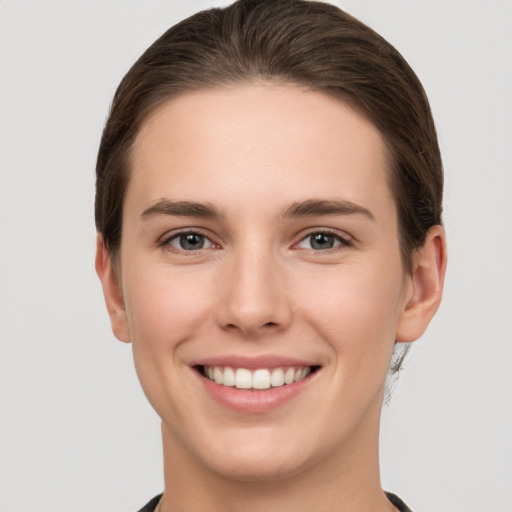 Joyful white young-adult female with short  brown hair and grey eyes