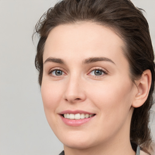 Joyful white young-adult female with medium  brown hair and grey eyes