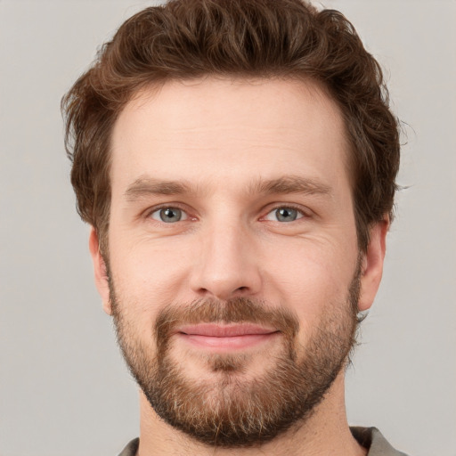 Joyful white young-adult male with short  brown hair and grey eyes