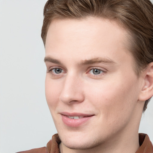 Joyful white young-adult male with short  brown hair and blue eyes