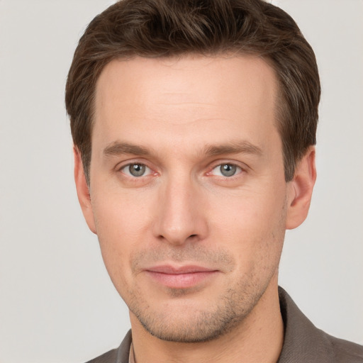 Joyful white young-adult male with short  brown hair and grey eyes