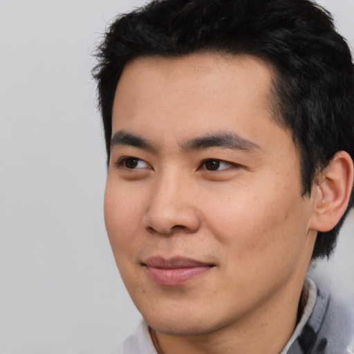 Joyful asian young-adult male with short  black hair and brown eyes
