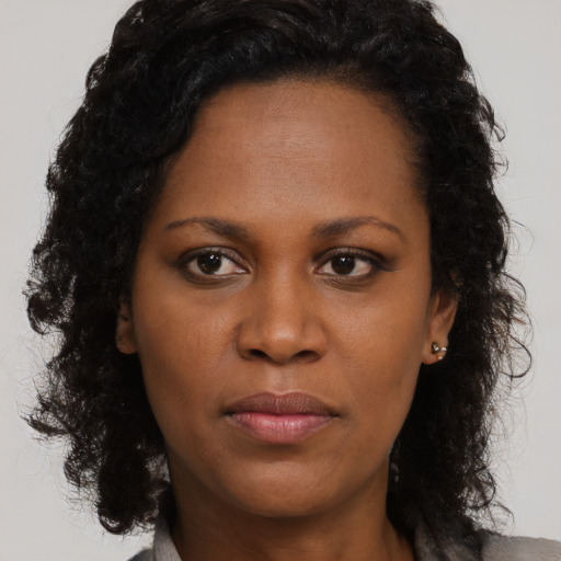 Joyful black young-adult female with long  brown hair and brown eyes