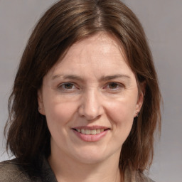 Joyful white adult female with medium  brown hair and grey eyes