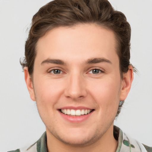 Joyful white young-adult male with short  brown hair and green eyes