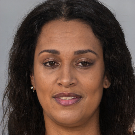 Joyful black adult female with long  brown hair and brown eyes