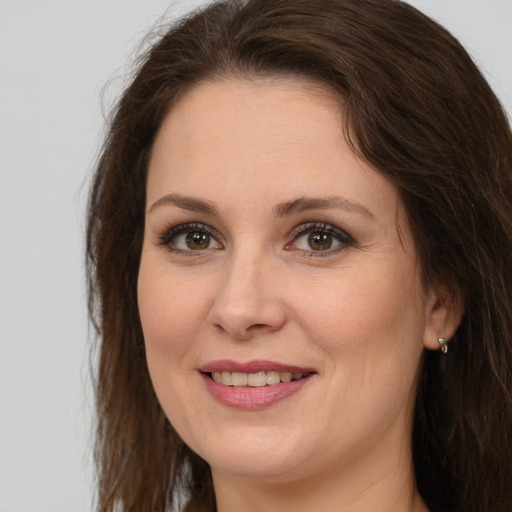 Joyful white adult female with long  brown hair and grey eyes