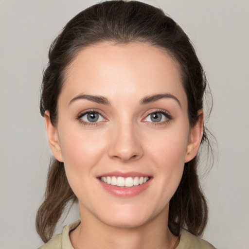 Joyful white young-adult female with medium  brown hair and grey eyes