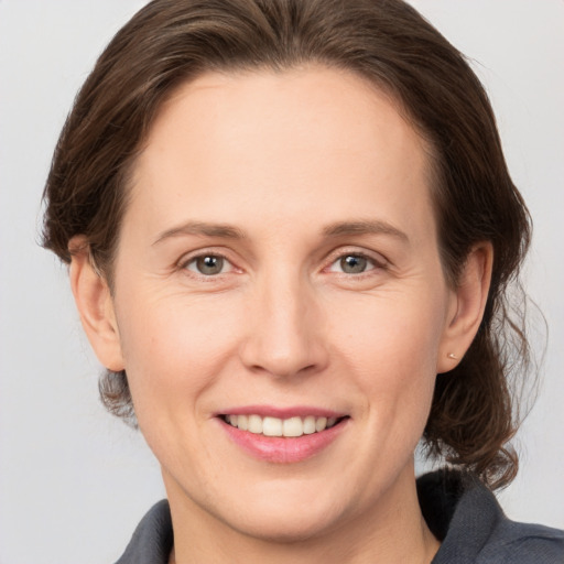 Joyful white young-adult female with medium  brown hair and grey eyes