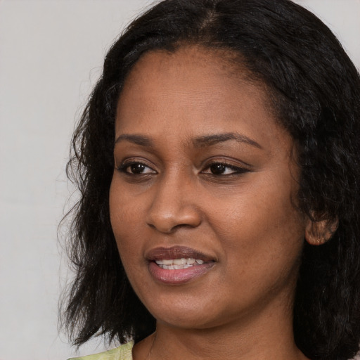 Joyful black adult female with long  black hair and brown eyes