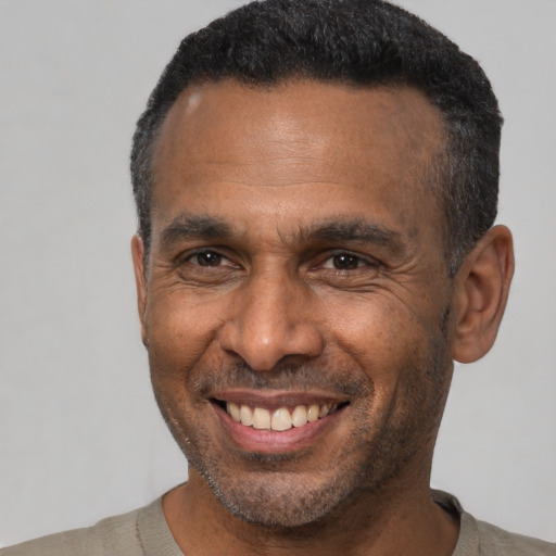 Joyful black adult male with short  black hair and brown eyes