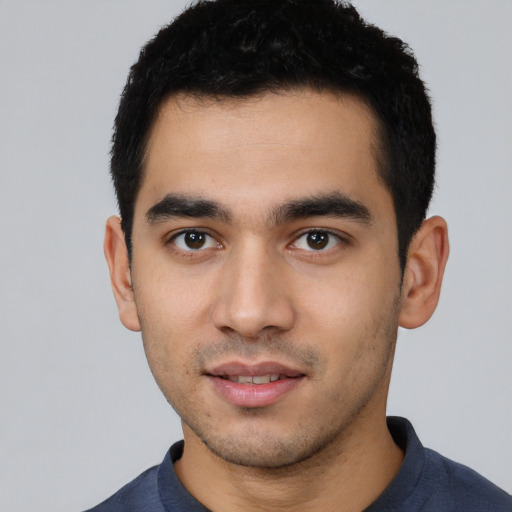 Joyful latino young-adult male with short  black hair and brown eyes