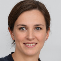 Joyful white young-adult female with medium  brown hair and grey eyes