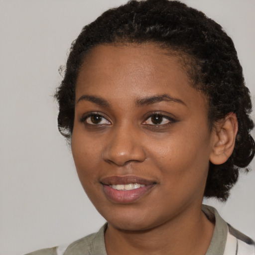 Joyful black young-adult female with short  black hair and brown eyes