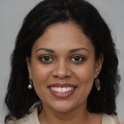 Joyful black young-adult female with long  brown hair and brown eyes