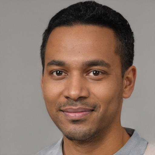 Joyful black young-adult male with short  black hair and brown eyes
