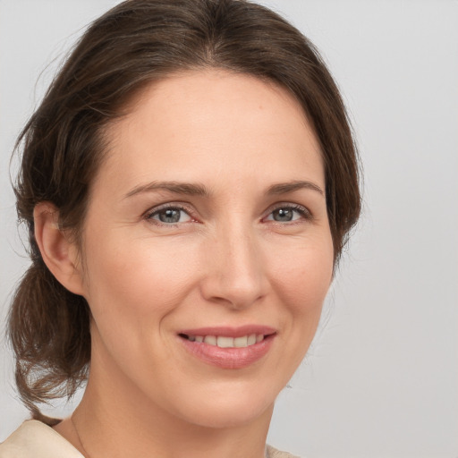 Joyful white young-adult female with medium  brown hair and grey eyes