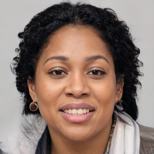 Joyful black young-adult female with long  brown hair and brown eyes