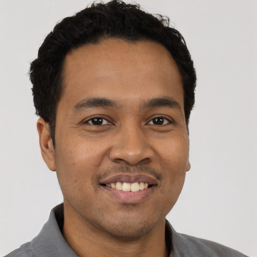 Joyful latino young-adult male with short  black hair and brown eyes