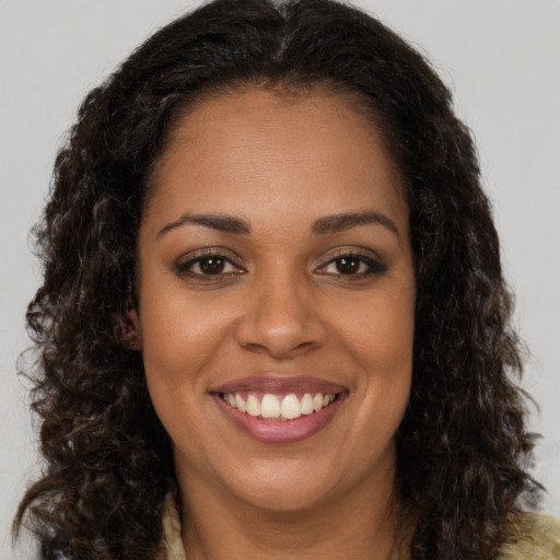 Joyful black young-adult female with long  brown hair and brown eyes