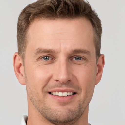 Joyful white young-adult male with short  brown hair and grey eyes