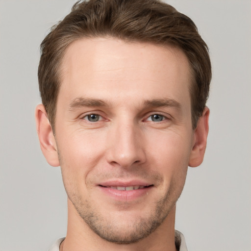 Joyful white young-adult male with short  brown hair and grey eyes