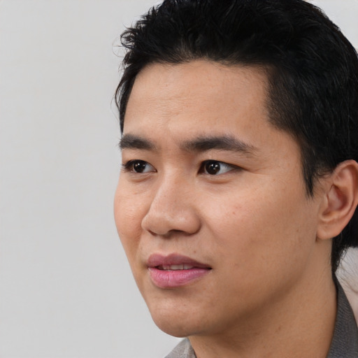 Joyful latino young-adult male with short  black hair and brown eyes