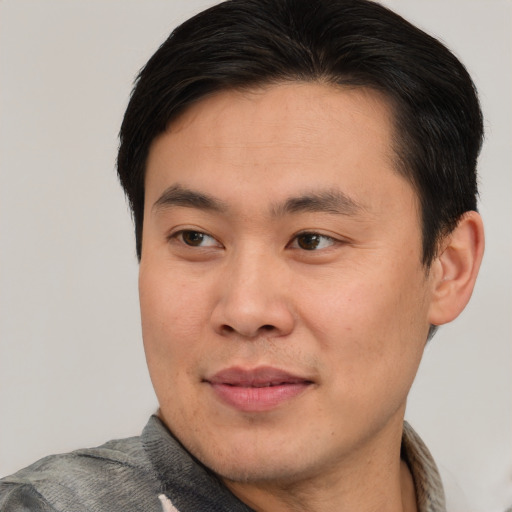 Joyful asian young-adult male with short  brown hair and brown eyes