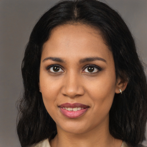Joyful black young-adult female with long  brown hair and brown eyes