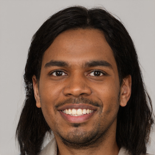 Joyful black young-adult male with medium  black hair and brown eyes