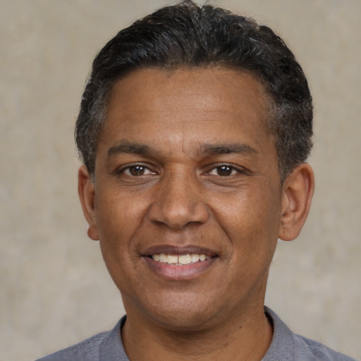 Joyful black adult male with short  black hair and brown eyes
