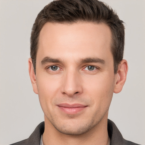 Joyful white young-adult male with short  brown hair and grey eyes