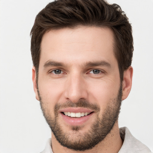 Joyful white young-adult male with short  brown hair and grey eyes