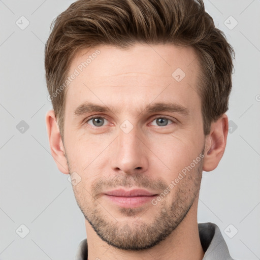 Joyful white young-adult male with short  brown hair and grey eyes