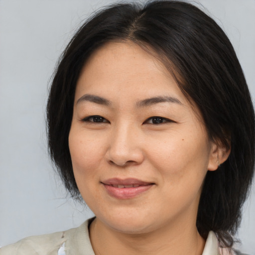 Joyful asian adult female with medium  brown hair and brown eyes