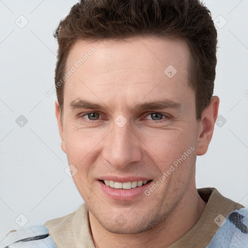 Joyful white young-adult male with short  brown hair and grey eyes