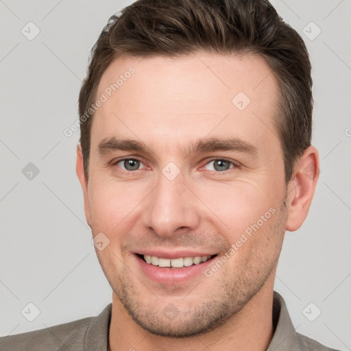 Joyful white young-adult male with short  brown hair and grey eyes