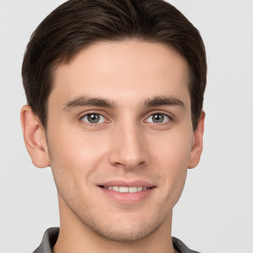 Joyful white young-adult male with short  brown hair and grey eyes