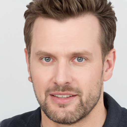 Joyful white adult male with short  brown hair and blue eyes