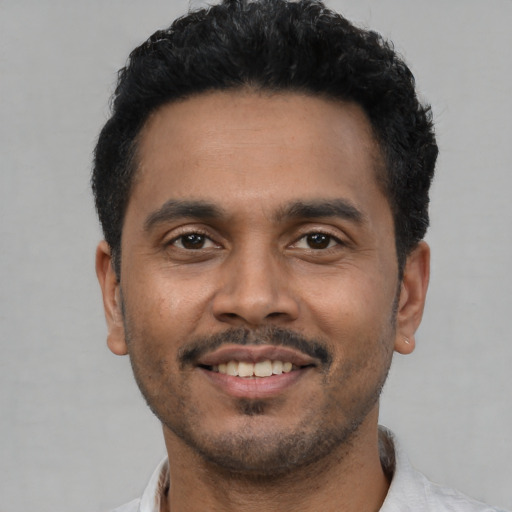 Joyful latino young-adult male with short  black hair and brown eyes