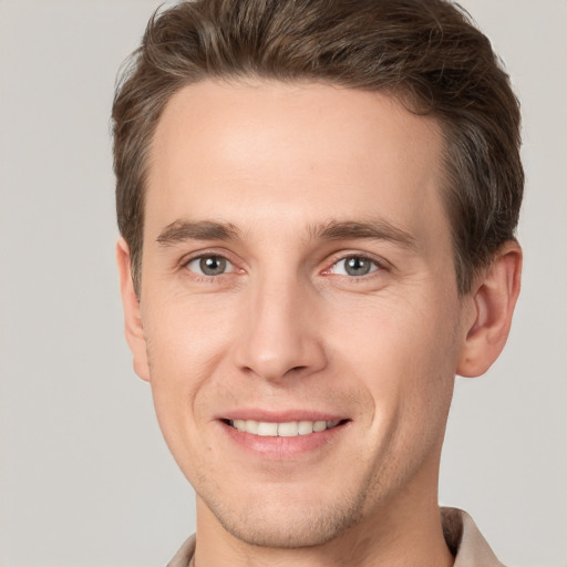 Joyful white young-adult male with short  brown hair and grey eyes