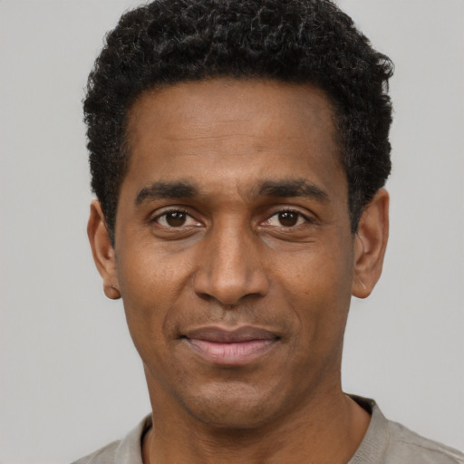 Joyful black adult male with short  black hair and brown eyes