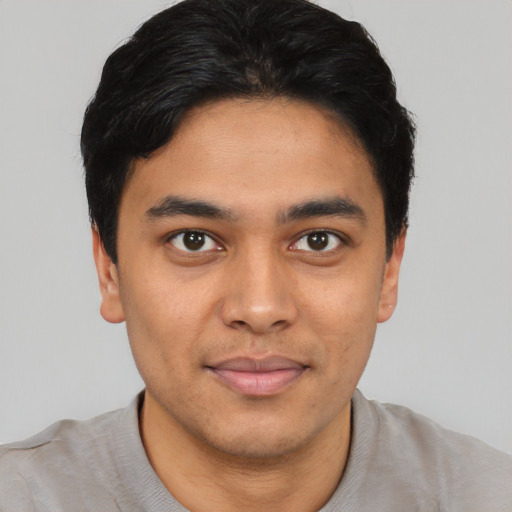 Joyful latino young-adult male with short  black hair and brown eyes