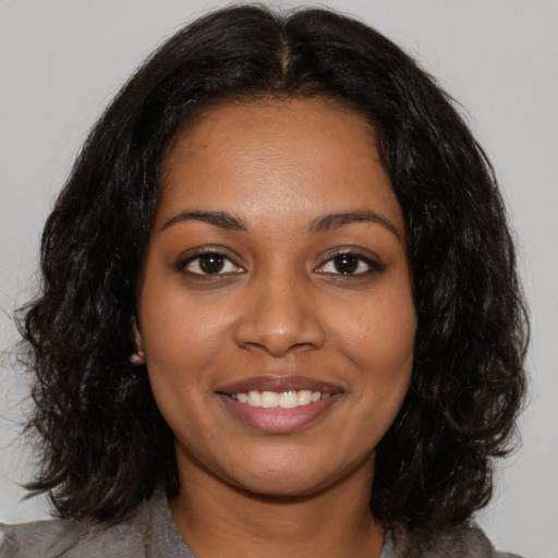 Joyful black young-adult female with medium  brown hair and brown eyes