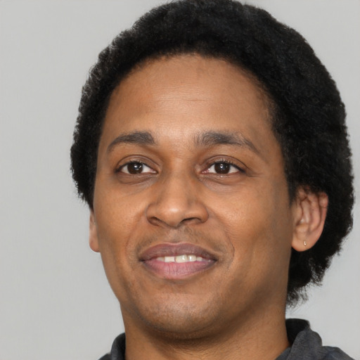 Joyful black adult male with short  black hair and brown eyes