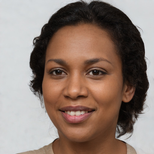 Joyful black young-adult female with long  brown hair and brown eyes