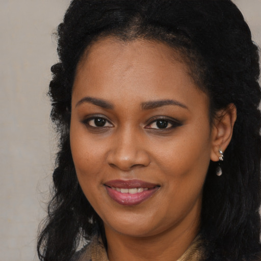 Joyful black young-adult female with long  brown hair and brown eyes