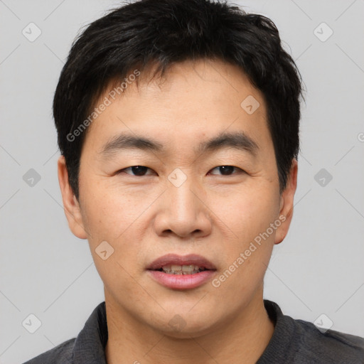 Joyful asian young-adult male with short  black hair and brown eyes